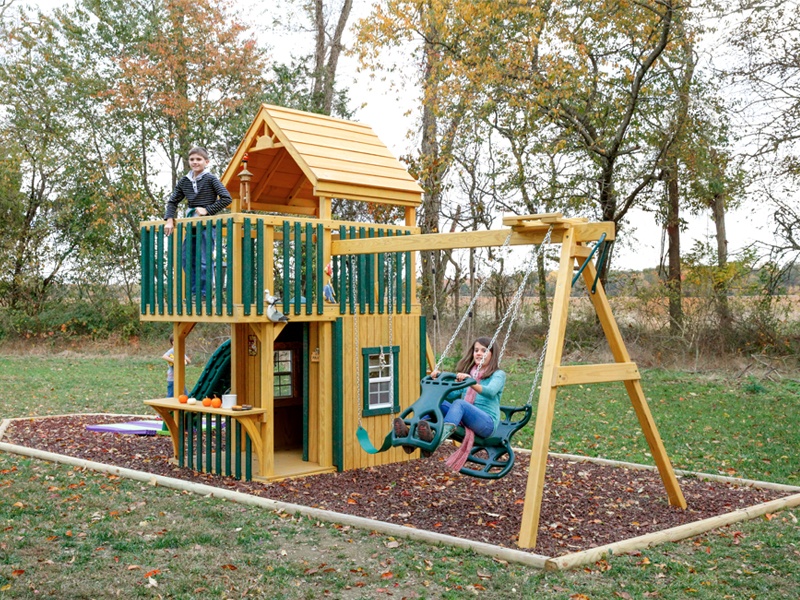 Trading Post 26'x10' Playset with 5x8 Tower, Step Ladder, Hand Rail, Wood Roof, 5x5 Trading Post Enclosure, Green Poly Slats, 10’ Wonder Wave Slide, Spotlight, 3-Position 7’ High Swing Beam, Belt Swing, Child’s Seat with Rope, Plastic Glider, & (6) Anchors