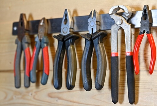 pliers and other metals tools hang from a magnetic strip on the shed wall