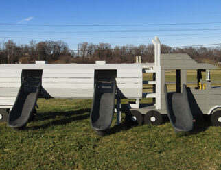 a gray semi truck with three slides in a grassy field